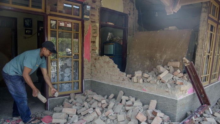Warga melintas di dekat rumah yang rusak pascagempa bumi di Desa Cibeureum, Kertasari, Kabupaten Bandung, Jawa Barat, Rabu (18/9/2024). Menurut data sementara BPBD Provinsi Jawa Barat,  gempa berkekuatan 5.0 Magnitudo tersebut mengakibatkan 8 unit rumah, 2 fasilitas kesehatan, 1 sarana pendidikan, dan 1 tempat ibadah mengalami kerusakan. ANTARA FOTO/Novrian Arbi/Spt.