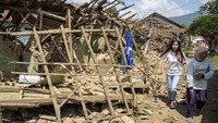 Warga melintas di dekat rumah yang rusak pascagempa bumi di Desa Cibeureum, Kertasari, Kabupaten Bandung.  