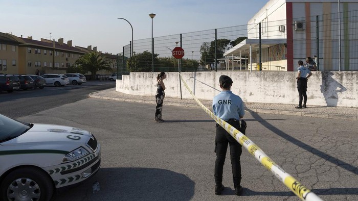 A police officer kisses a girl outside a school where a 12-year-old boy stabbed and injured six other children in Azambuja, near Lisbon, Tuesday, Sept. 17, 2024. (AP Photo/Ana Brigida)