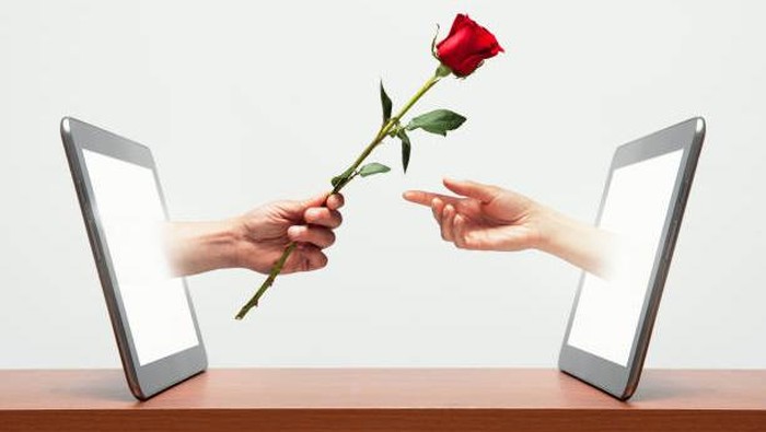 Ilustrasi Long Distance Relationship (LDR). Mans hand coming from digital tablet handing womans hand a red rose