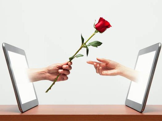 Ilustrasi Long Distance Relationship (LDR). Mans hand coming from digital tablet handing womans hand a red rose