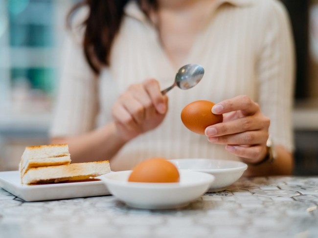 Image of a young Chinese woman having traditional style Malaysian breakfast in restaurant