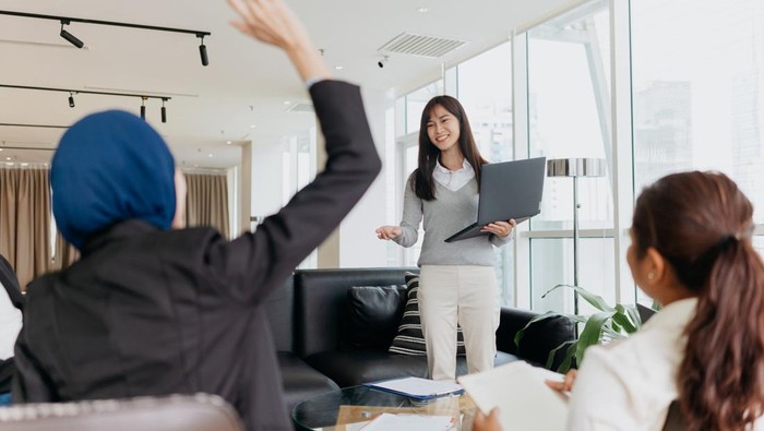 An Asian Chinese woman business entrepreneur giving a speech and presenting ideas and strategies to her team in office