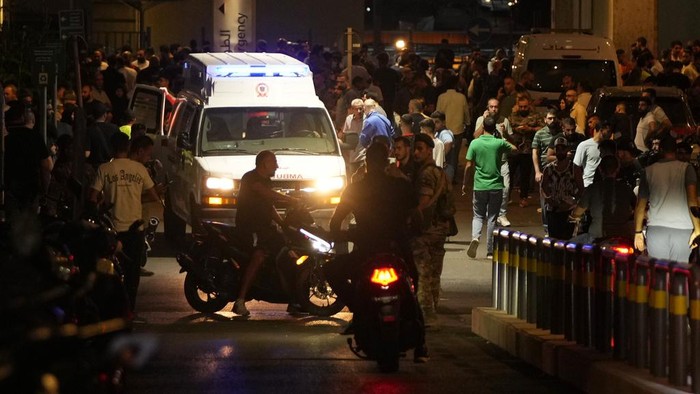 People gather outside the American University hospital after the arrival of several people who were wounded by exploding handheld pagers, in Beirut, Lebanon, Tuesday, Sept. 17, 2024. (AP Photo/Hassan Ammar)