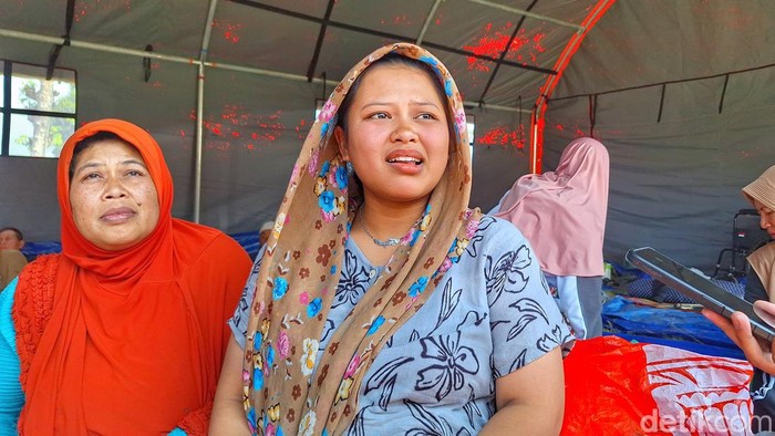 Febriani (baju abu), ditemani ibunya di tenda pengungsian.