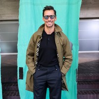 Model David Gandy bersolek dengan gaya dandy dalam padanan polo-shirt hitam, celana dan sepatu formal, berikut jaket parka. (Foto: Dave Benett/Getty Images for Burberry)