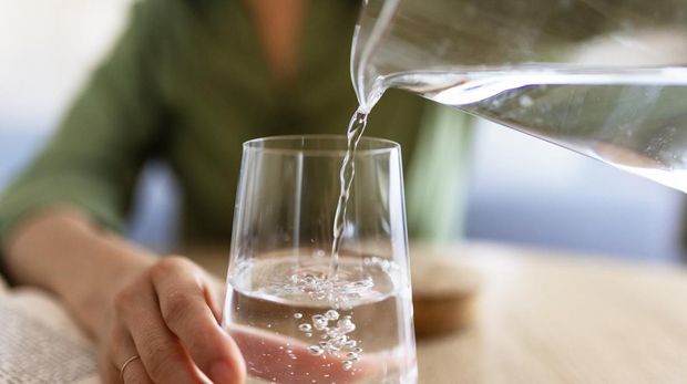 Ilustrasi minum air Close Up of Woman Pouring Water From Jug Into Glass