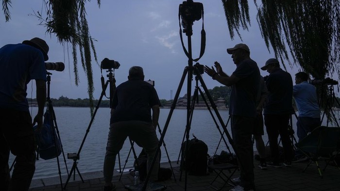 Kala Fotografer China Berburu Momen Bulan Purnama Para penggemar fotografi menyiapkan kamera mereka sambil menunggu untuk mengabadikan bulan purnama di Taman Beihai, Beijing, China, Rabu (18/9/2024).