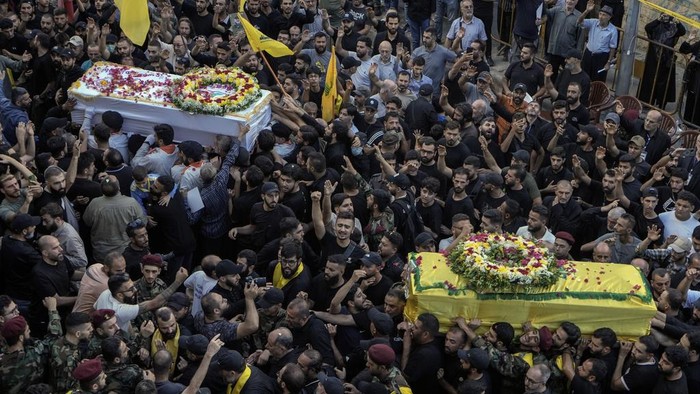 Momen Pemakaman Korban Ledakan Pager di Lebanon Hezbollah fighters salute as they stand next to the coffins of four victims who were killed Tuesday after their handheld pagers exploded, during their funeral procession in the southern suburb of Beirut, Lebanon, Wednesday, Sept. 18, 2024. (AP Photo/Bilal Hussein)