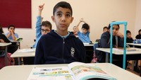 Di Sekolah Palestina yang telah lama berdiri di Doha, ia duduk dengan sabar sementara teman-teman sekelasnya menuliskan sesuatu dan meninggikan suaranya bersama mereka saat mereka menjawab pertanyaan guru.