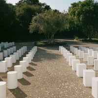 Terinspirasi fashion show Jacquemus yang simple dan elegan, bangku-bangku tamu pun ditata minimalis berwarna putih, tanpa dekorasi rumit menuju ‘altar’. Hanya beberapa taburan kelopak bunga putih untuk memberi nuansa romantis. Foto: Instagram/@normanandblake @charlieputh @puthbrooke