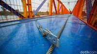 Jembatan berwarna oren itu menggunakan konsep jembatan gantung dengan tali-talinya.