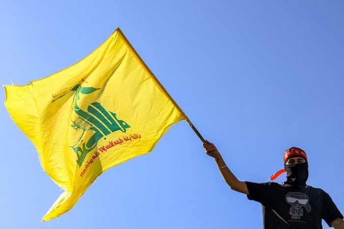 A masked demonstrator waves a flag of the Lebanese Shiite movement Hezbollah during a demonstration supporting the Palestinians in Beirut on October 20, 2023, amid the ongoing battles between Israel and the Palestinian group Hamas. (Photo by JOSEPH EID / AFP)