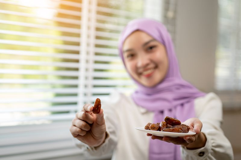 Asian Muslim woman eating dates and resting during fasting at home during Ramadan