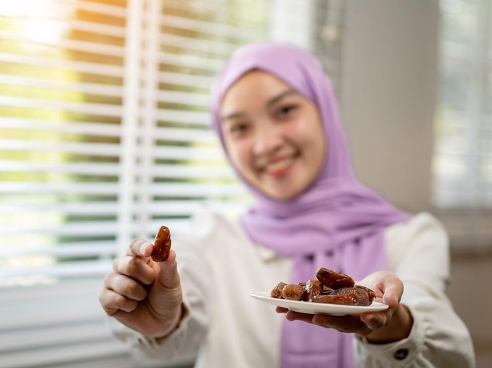 Asian Muslim woman eating dates and resting during fasting at home during Ramadan