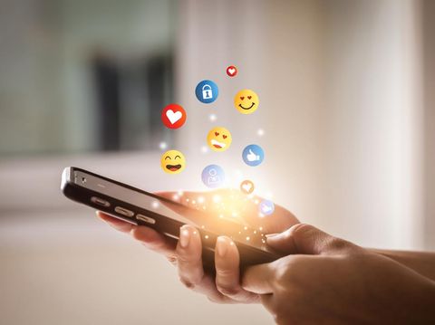 Young man using smartphone sending emojis. Mobile smartphone sending text messages emoji emoticon.