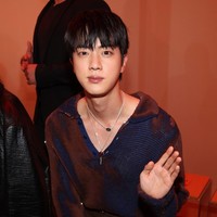 Dalam kesempatan itu, Jin BTS tampil menawan dalam balutan knitted sweater bernuansa oranye-biru, potongan celana coklat, sepatu loafers dan belt hitam. Foto: Getty Images