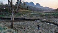 Warga melintas di dasar Waduk Bendo yang mengering di Kabupaten Ponorogo, Jawa Timur, Jumat (20/9/2024).