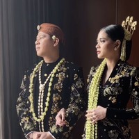 Nino dan istrinya yang akrab disapa Ica itu memilih menggunakan busana adat Jawa dalam upacara resepsi pernikahan mereka. Nino tampak gagah mengenakan beskap beludru hitam, lengkap dengan kain batik. Foto: dok. The Bride Story