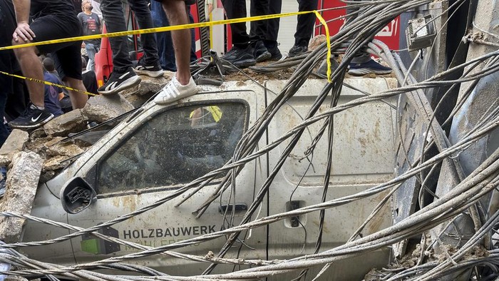 Potret Kerusakan di Lebanon Usai Serangan Israel People stand on top of a damaged car at the scene of a missile strike in the southern suburbs of Beirut, Friday, Sept. 20, 2024. (AP Photo/Bilal Hussein)