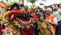 Warga keturunan Tionghoa memberi angpao pada penari naga saat menyaksikan kirab budaya Gotong Toapekong.