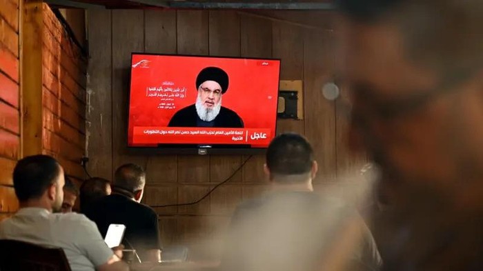 Sejumlah warga Lebanon menyimak pidato pemimpin Hezbollah, Hassan Nasrallah, yang disiarkan melalui televisi. (EPA)