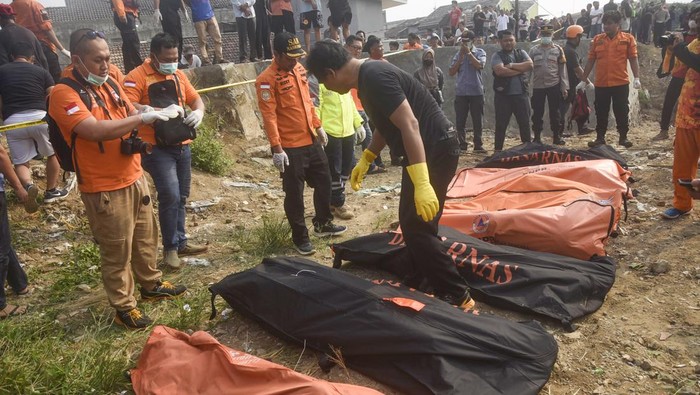 Sejumlah petugas BPBD Kota Bekasi dan polisi berdiri dengan latar depan kantong-kantong  berisi tujuh jenazah laki laki yang ditemukan mengambang di Kali Bekasi, Pondok Gede Permai, Jatiasih, Kota Bekasi, Minggu (22/9/2024). Kepolisian masih menyelidiki penyebab kematian tujuh orang tersebut. ANTARA FOTO/Rezas Ale/app/foc.