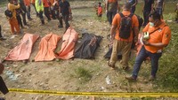 Sejumlah polisi memeriksa kantong-kantong berisi tujuh jenazah laki laki yang ditemukan mengambang di Kali Bekasi.