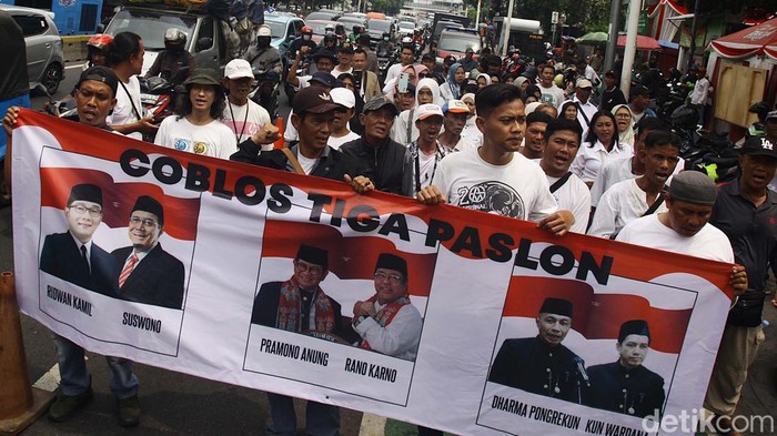 Aksi Coblos Tiga Paslon di Pilkada Jakarta Massa dari Jaringan Rakyat Miskin Kota (JRMK) Jakarta berunjuk rasa di depan kantor KPU Provinsi Jakarta, Jl Salemba Raya, Senin (23/09/2024). Unjuk rasa tersebut diwarnai aksi mencoblos 3 pasang cagub-cawagub Jakarta. Selain itu, JRMK menyatakan sikap memilih golput dalam Pilgub Jakarta karena ketiga paslon dinilai jadi alat bagi para elit untuk melanggengkan kekuasaan dan tidak memihak rakyat.