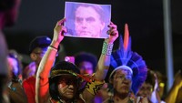 Seorang perempuan adat memegang foto mantan Presiden Brasil Jair Bolsonaro saat para aktivis menghadiri protes terhadap krisis iklim yang menyebabkan kebakaran hutan di negara itu.