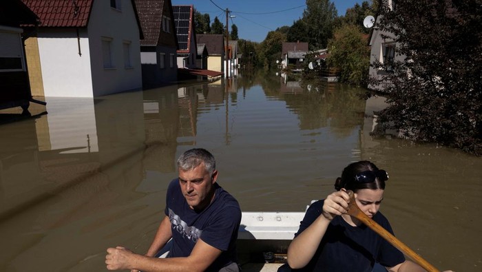People row a boat among houses flooded by the Danube River in the village of Ersekcsanad, Hungary, September 22, 2024. REUTERS/Marko Djurica