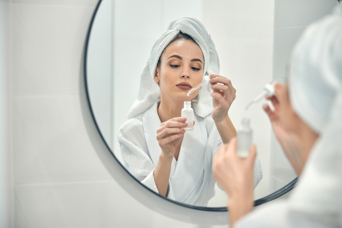 Ilustrasi wanita memakai serum wajah alternatif pengganti retinol.