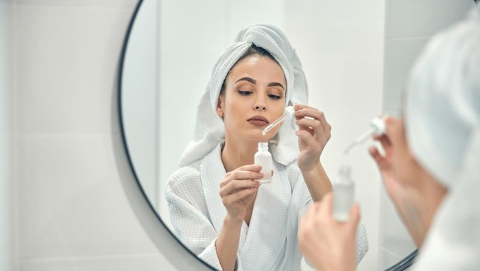 Ilustrasi wanita memakai serum wajah alternatif pengganti retinol.