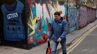 Seorang warga berjalan melewati mural yang mendukung warga Palestina yang menampilkan jurnalis foto Gaza Motaz Azaiza, di tengah konflik Israel-Hamas yang sedang berlangsung, di Dublin, Irlandia, Minggu (22/9/2024) waktu setempat.
