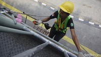 Pekerja menyelesaikan program pemeliharaan jembatan penyeberangan orang (JPO) di Jalan Salemba Raya, Selasa (24/9/2024).