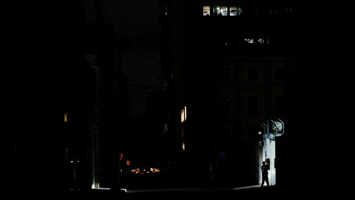 Warga Ekuador Kini Hidup Tanpa Listrik 12 Jam Per Hari Esther Gualtieri and her sons Rafael and Miguel Diaz Gualtieri look at a screen during a power outage, in Quito, Ecuador September 23, 2024. REUTERS/Karen Toro
