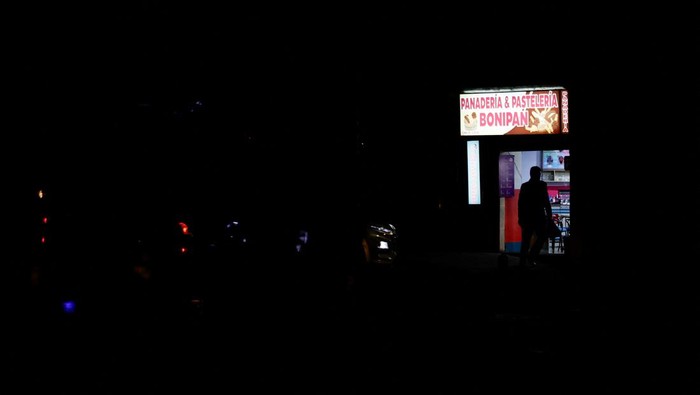 Warga Ekuador Kini Hidup Tanpa Listrik 12 Jam Per Hari Esther Gualtieri and her sons Rafael and Miguel Diaz Gualtieri look at a screen during a power outage, in Quito, Ecuador September 23, 2024. REUTERS/Karen Toro