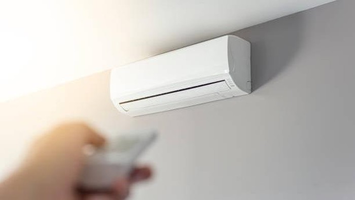 A man shutting down the air conditioner with remote control. Selective focus on the air conditioner. cuci AC rutin