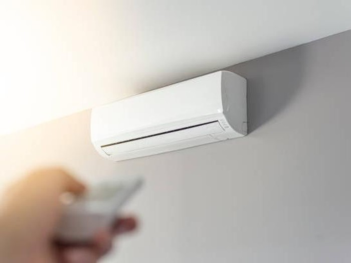 A man shutting down the air conditioner with remote control. Selective focus on the air conditioner.