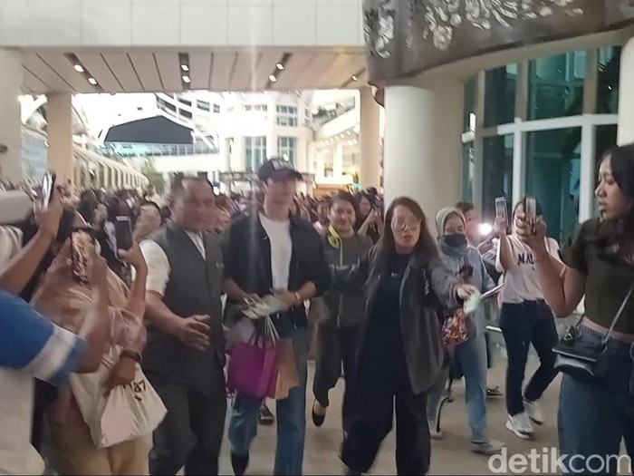 Jung Hae In (topi hitam) dan Kim Yoon Ji alias Jung So Min mendarat di Bandara Internasional Ngurah Rai, Selasa (24/9/2024), sekira pukul 23.10 Wita. (Aryo Mahendro/detikBali).