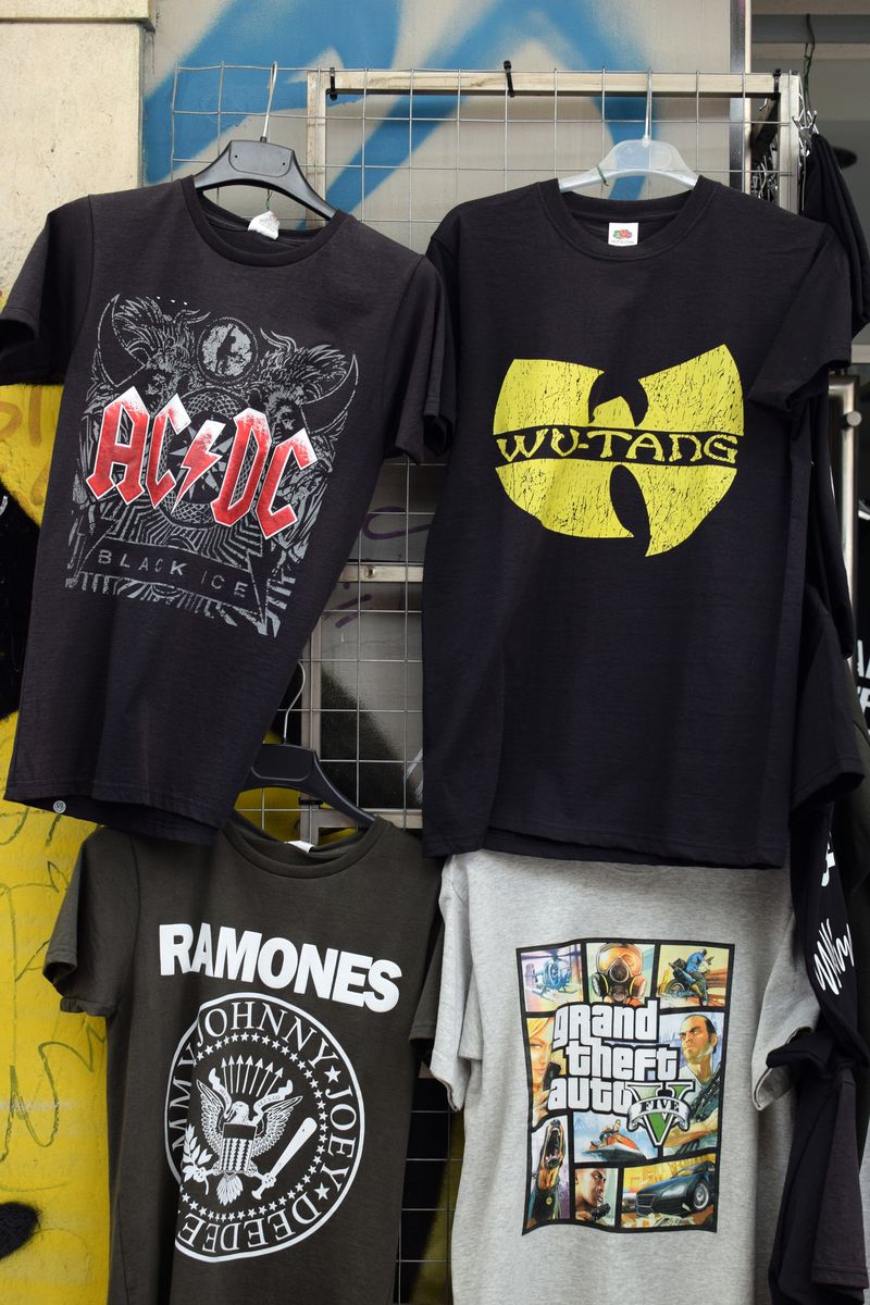 Athens, Greece - August 4, 2016: Rock and hip hop music t-shirts for sale printed with band logos by The Ramones, AC/DC, Wu-Tang Clan and video game Grand Theft Auto.