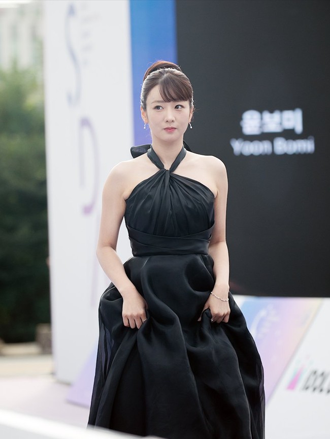 Sekretaris Na di drama Korea Queen of Tears, Yoon Bo Mi mengenakan halter dress berwarna hitam. Tampil bak Disney princess di Seoul International Drama Awards 2024 dengan bun hair. Foto: Instagram
