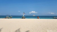 Lanskap pantai di Gili Labak yang sangat kontras antara pasir putih, langit biru dan laut yang lebih gelap. 