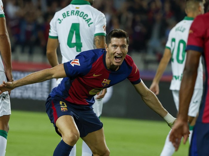 Barcelona's Robert Lewandowski, center, celebrates with Barcelona's Jules Kounde, front, after scoring the opening goal during a Spanish La Liga soccer match between Barcelona and Getafe at the Olympic stadium in Barcelona, Spain, Wednesday, Sept. 25, 2024. (AP Photo/Joan Monfort)
