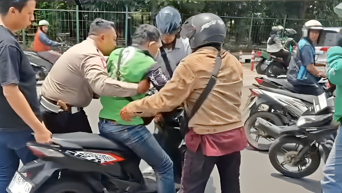 Aksi sigap ditunjukkan polantas yang membantu driver ojol yang sakit saat membawa penumpang. Driver ojol itu dibantu hingga dapat melanjutkan perjalanannya. (dok IG @tmcpoldametro)