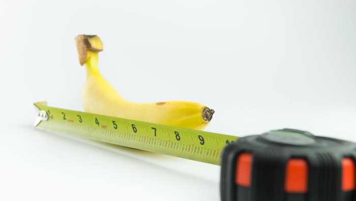 Close-up of measuring the size of banana on white background