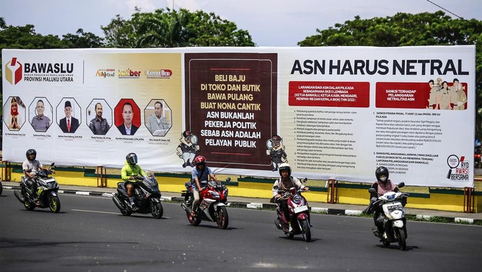 Sejumlah kendaraan roda dua melintas di depan baliho sosialisasi yang terpasang di pinggir jalan Pemuda Ternate, Maluku Utara, Jumat (27/9/2024). Badan Pengawas Pemilu (Bawaslu) Provinsi Maluku Utara memasang baliho sosialisasi tersebut untuk mengimbau seluruh ASN untuk netral dalam Pilkada serentak 2024 di Maluku Utara dan mengajak warga untuk menolak politik uang. ANTARA FOTO/Andri Saputra/nym.