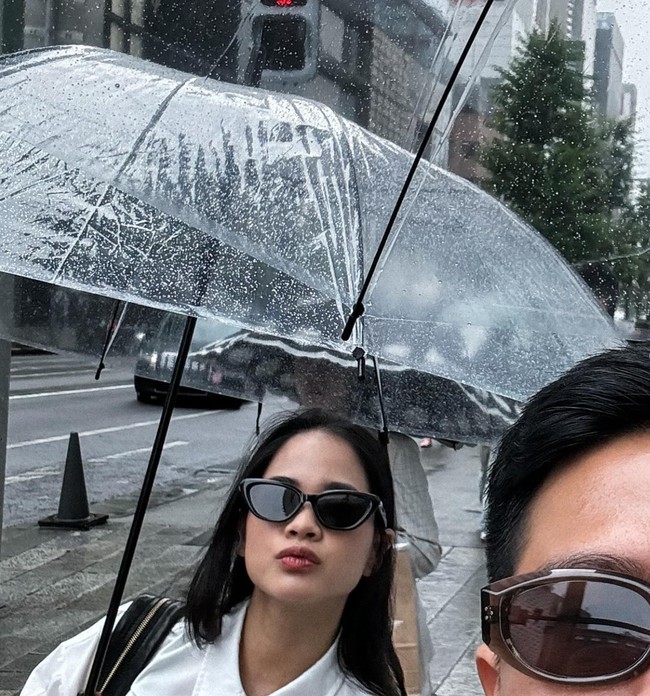 Meski Jepang tengah diguyur hujan namun Nino dan istrinya tetap terlihat ceria dan bersemangat menghabiskan bulan madu mereka. Sambil sama-sama memegang payung, keduanya pun wefie di jalanan Jepang. Foto: Instagram/@ninokayam