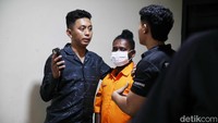 Tampak keduanya mengenakan pakaian tahanan berwarna oranye. Rambut salah satu tersangka tampak terikat.