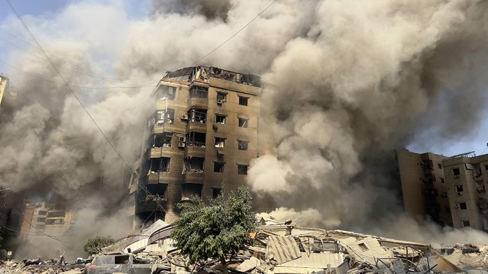 Smoke rises as a building collapses in Beiruts southern suburbs, Saturday, Sept. 28, 2024. (AP Photo/Hussein Malla)